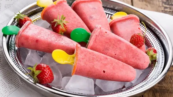 Erfrischendes Erdbeer-Eis am Stiel selber machen. Auf einem Silbertablett mit Eiswürfeln und frischen Erdbeeren serviert.