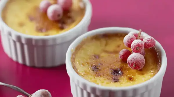 Deux flans aux œufs, dorés et caramélisés, ornés de groseilles givrées. Un délice visuel et gustatif.