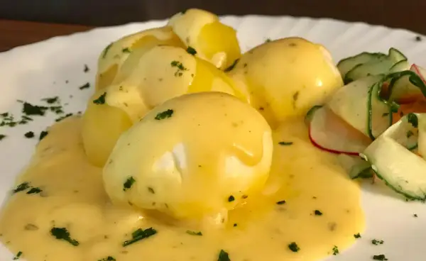 Senfeier rezept: pochiere Eier in cremiger Sauce mit Kartoffeln und einem frischen Gurkensalat.