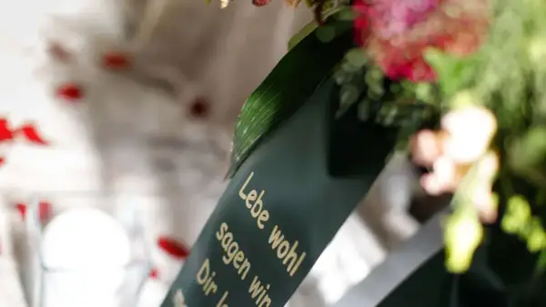 Trauerkranz mit Spruch "Lebe wohl". Mögliche Nachteile beim Kirchenaustritt für die Beerdigung.