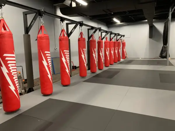 A row of red punching bags hangs from a metal rack, demonstrating how to hang a punching bag for optimal training.