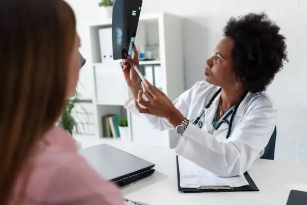 Lekarka analizuje mammografię, wskazując pacjentce podejrzane zmiany, które mogą sugerować kategorię BIRADS 4.