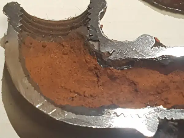 Sezione di tubo metallico con incrostazioni marroni che mostrano come evitare la formazione di calcare nelle tubazioni.