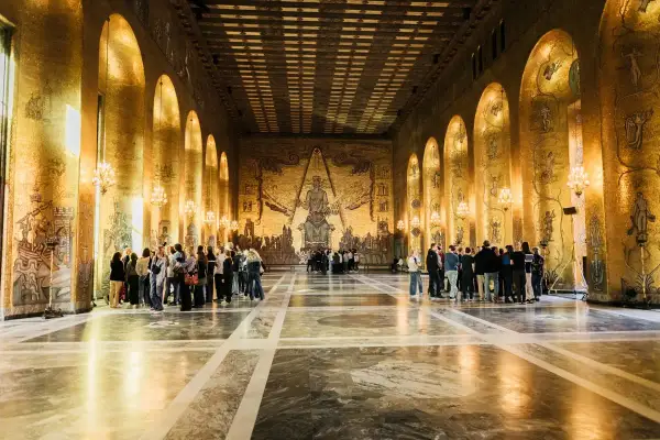 Gyllene salen i Stockholms stadshus, med sina glänsande mosaikväggar och imponerande tak, fylld av besökare som beundrar konstverken.