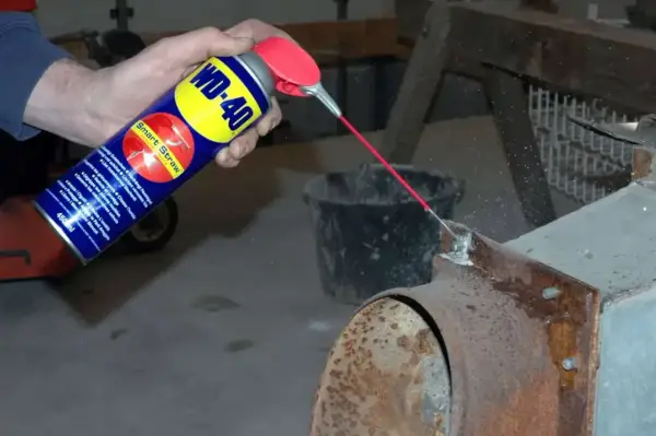 WD-40 wird auf einen verrosteten Kaminofen gesprüht, um Rost zu entfernen.