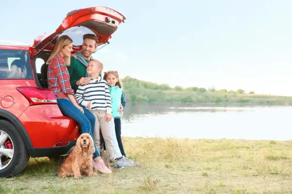 Famille heureuse avec leur chien près d'un lac, profitant d'un voyage dans un pays dog friendly.