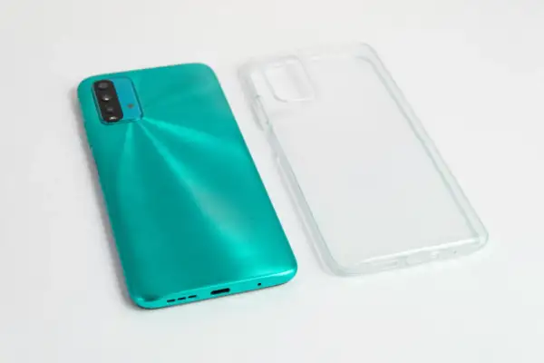 Turkusowy telefon i przezroczyste etui obok. Zastanawiasz się, czym umyć etui od telefonu, by znów wyglądało jak nowe?