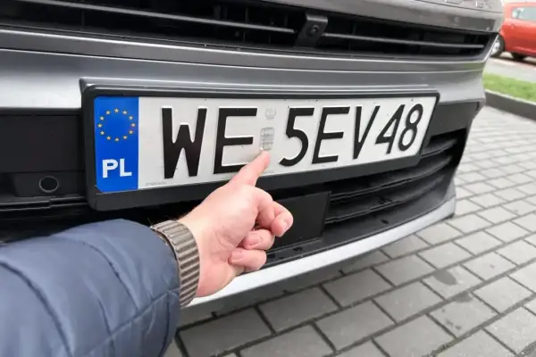 Palec wskazujący na hologram na tablicy rejestracyjnej. Uniknij kary za nieprzerejestrowanie pojazdu, dbając o aktualne dokumenty.