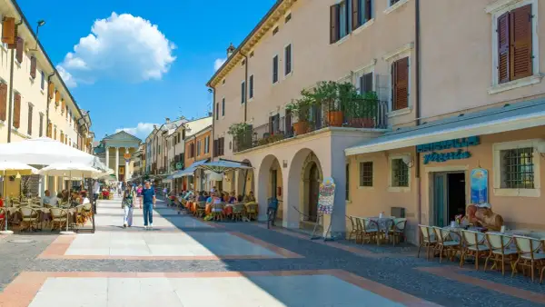 Passeggiata nel bardolino centro storico, con tavolini all'aperto e gente che gode del sole.