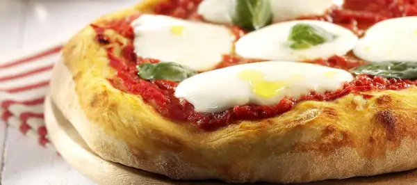 En närbild av en klassisk italiensk mat: pizza Margherita med krämig mozzarella, röd tomatsås och färsk basilika.