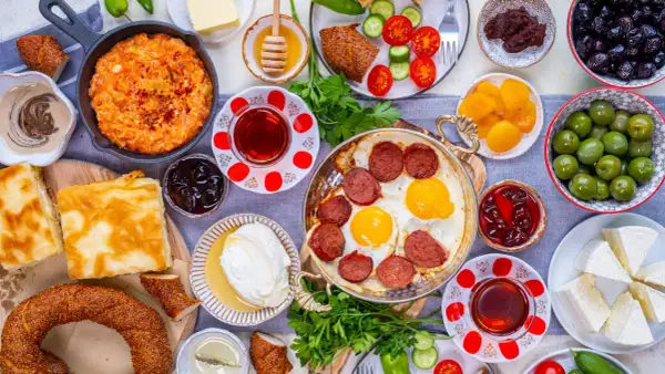 Reichhaltiges türkisches Frühstück: Eier mit Sucuk, Käse, Oliven, Honig und Gebäck. Welches Lebensmittel hat die meisten Kalorien? Wahrscheinlich das Gebäck oder die Wurst.