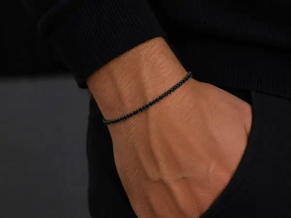Pulsera barbada oro con diamantes negros en muñeca masculina. Elegancia y estilo en cada detalle.