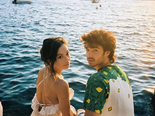 Anna Castillo y Álvaro Mel disfrutan de un atardecer junto al mar, con barcos al fondo.
