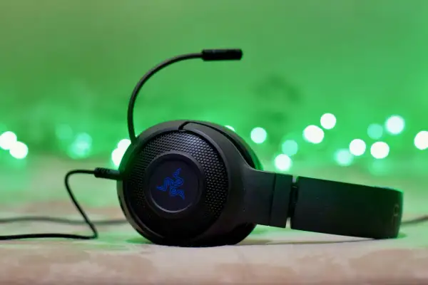 Słuchawki gamingowe Razer z mikrofonem, podłączone przez combo jack, na tle zielonych światełek.
