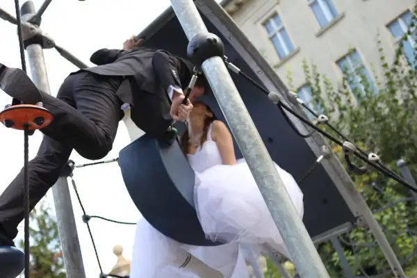 Młoda para w ślubnych strojach całuje się na placu zabaw. Czy lakarnum ma narzeczoną? Tak, i to piękną!