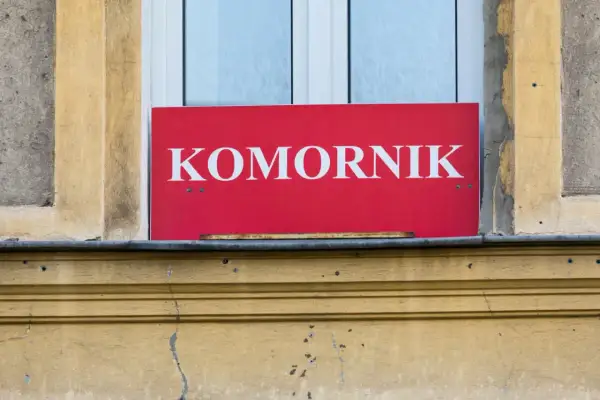 Czerwony szyld z napisem "KOMORNIK" nad oknem. Może oznaczać, że to miejsce, gdzie można dowiedzieć się o kwocie wolnej od zajęcia.