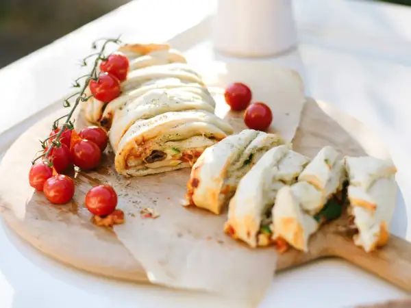 Ein köstlicher Stromboli, gefüllt mit Tomaten, Oliven und Käse, wird mit frischen Kirschtomaten garniert. Perfekt zum Stromboli essen!