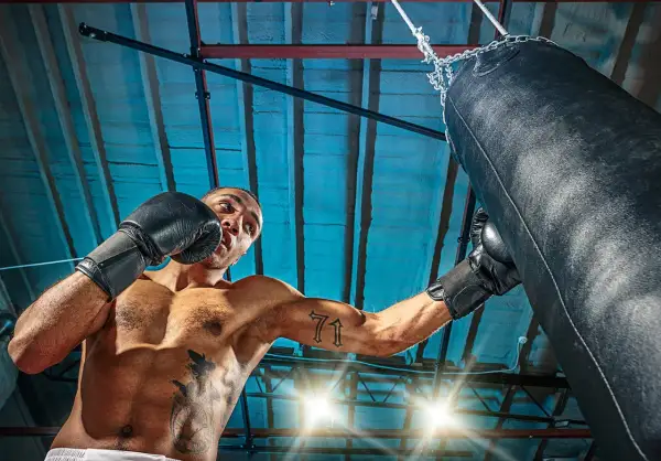 Man i boxningshandskar tränar sparra boxning mot en sandsäck i ett gym.