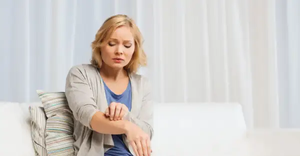 Donna si gratta il braccio, sofferente per l'aria secca che le irrita la pelle.