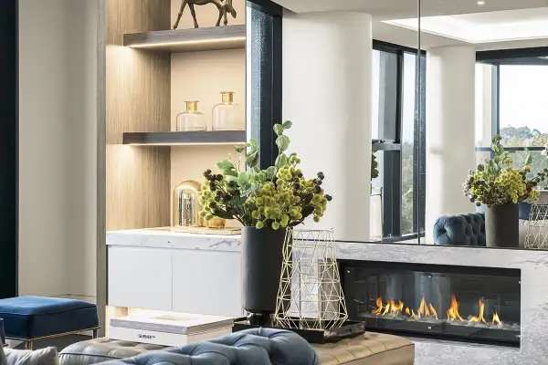 Un elegante camino bioetanolo come funziona: fiamme vive su un letto di sassi bianchi, con decorazioni moderne e arredi di lusso.