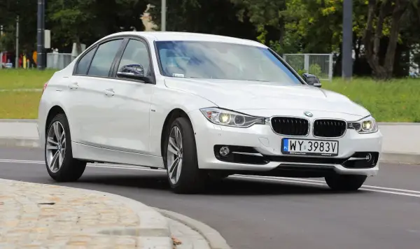 Białe BMW 318i z polskimi tablicami rejestracyjnymi WY 3983V jedzie po drodze.