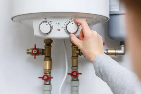 Main tenant ajuste le chauffe-eau pour éviter la pression d'eau chaude.