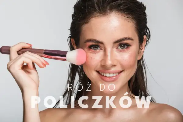 Uśmiechnięta kobieta z pędzlem do różu na policzku. Dowiedz się, jak nakładać róż dla naturalnego efektu.