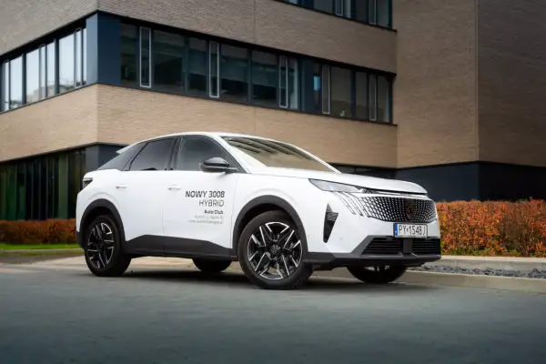 Biały Peugeot 3008 hybryda plug-in zaparkowany przed nowoczesnym budynkiem.