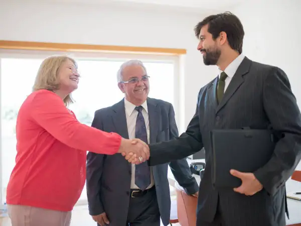 Coppia anziana stringe la mano a un consulente finanziario, discutendo del mutuo fino a che età.