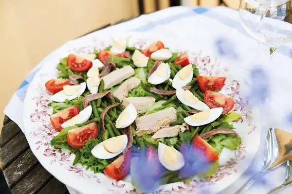 En härlig sallad nicoise med tonfisk, ägg, gröna bönor och tomater på en vacker tallrik.