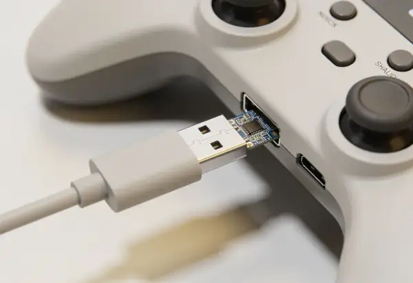 Szary kontroler z podłączonym kablem USB. Dowiedz się, jak podłączyć pada od PS4 do Xbox One, używając tego adaptera.