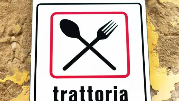Segnale con forchetta e cucchiaio incrociati, che indica una trattoria. Un invito a gustare sapori autentici, diverso dall'osteria.