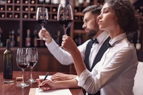 Para degustacji wina: kobieta i mężczyzna oceniają smak wina, notując wrażenia.