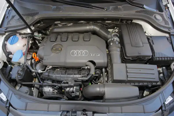 Widok komory silnika z widocznym silnikiem 2.0 TFSI Audi, zbiornikiem płynu chłodniczego i filtrem powietrza.