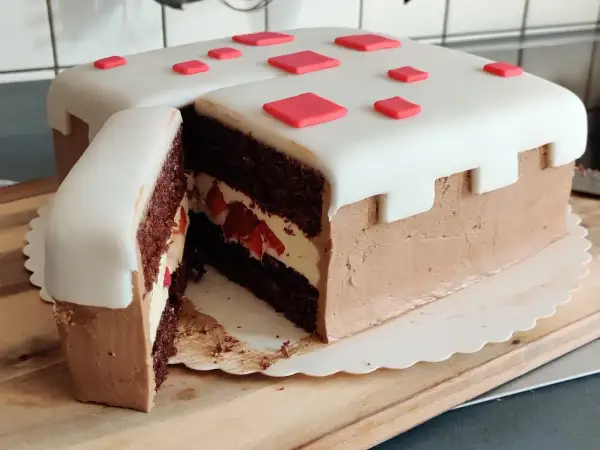 En chokladtårta med vit marsipan och röda dekorationer, inspirerad av Minecraft. Perfekt för ett Minecraft tårta recept!
