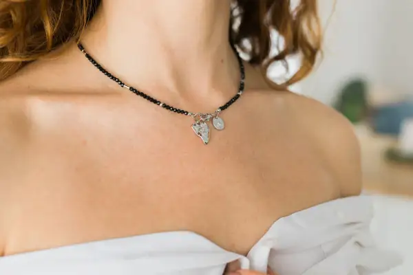 Delikatny choker z czarnych koralików i zawieszkami, podkreślający subtelność. Co oznacza choker na szyi? To ozdoba, która dodaje elegancji.