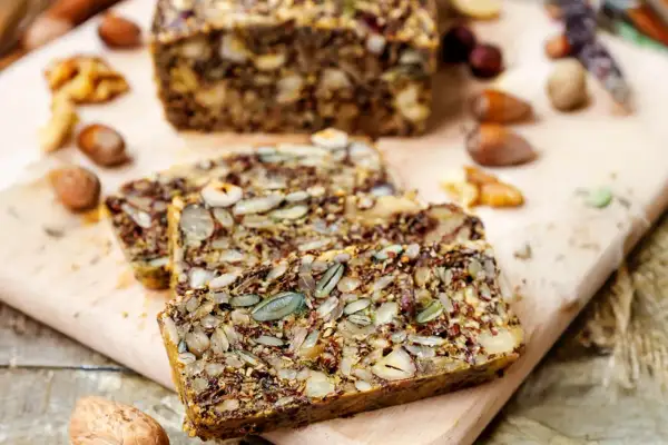 Ein rustikales Keto Brot Rezept mit vielen Kernen und Nüssen, auf einem Holzbrett serviert.