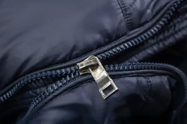 Detaljerad bild av en mörkblå jacka med en metallisk dragkedja. Kanske dags att laga dragkedja?