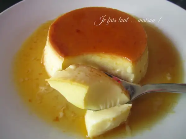 Une cuillère prélève un morceau d'un délicieux crème renversée maison, baignant dans son caramel doré.