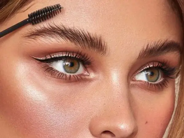 Cepillo peinando unas cejas perfectas para un laminado de cejas impecable.