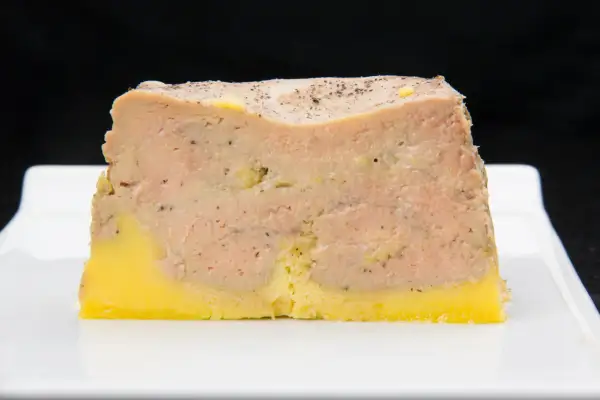 Tranche de pâté en croûte, avec une couche de viande rose et une base jaune, prête pour la cuisson.