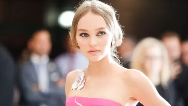Lily-Rose Depp, con un vestido rosa y maquillaje dramático, posa con elegancia.