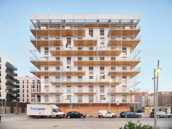 Edificio moderno con balcones de madera y metal. Posiblemente pisos de protección oficial en Barcelona, La Caixa, con vehículos aparcados.