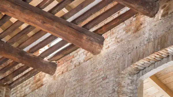 Trave in legno deteriorate e mattoni a vista: segnali evidenti per capire se un tetto è da rifare.