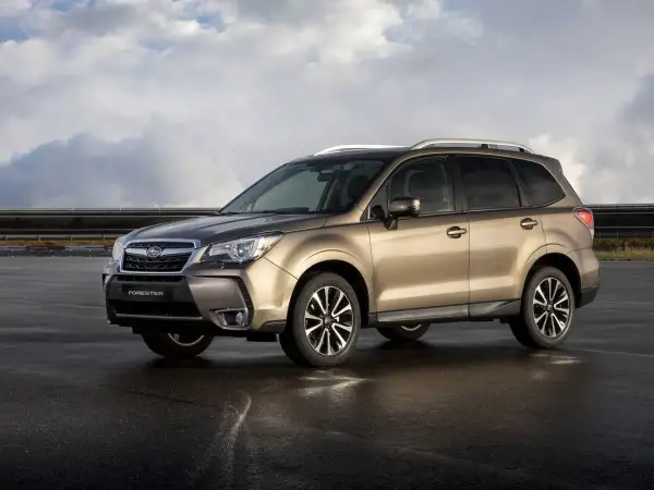Subaru Forester color bronce, estacionado en asfalto mojado, con nubes en el cielo. A pesar de su apariencia, algunos **subaru forester problemas** son conocidos.