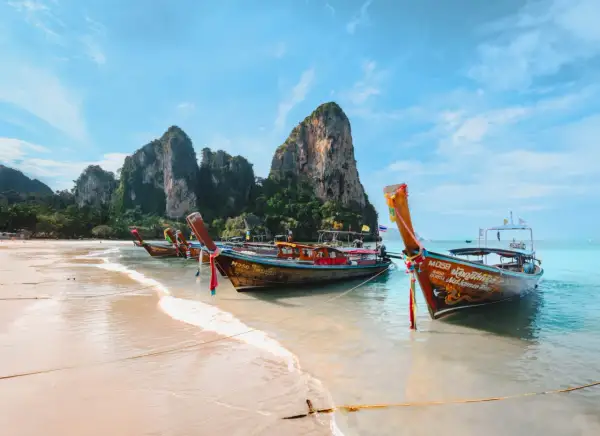 Bateaux traditionnels sur une plage de sable fin, parfaits pour organiser son voyage en Thaïlande et explorer les îles.