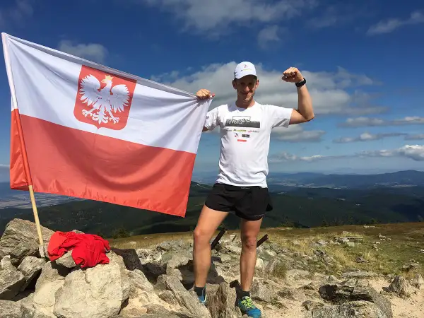 Zdobywca Korony Polskich Gór z biało-czerwoną flagą na szczycie.