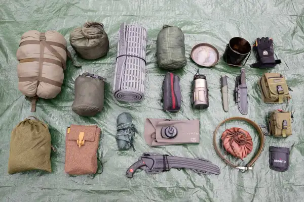 Outdoor-Ausrüstung: Schlafsack, Isomatte, Messer, Kochgeschirr, Handschuhe, Taschen und eine bpa-freie Trinkflasche.