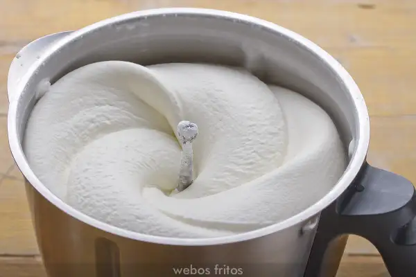 Crema de batir perfectamente montada en un bol de metal, lista para decorar postres.