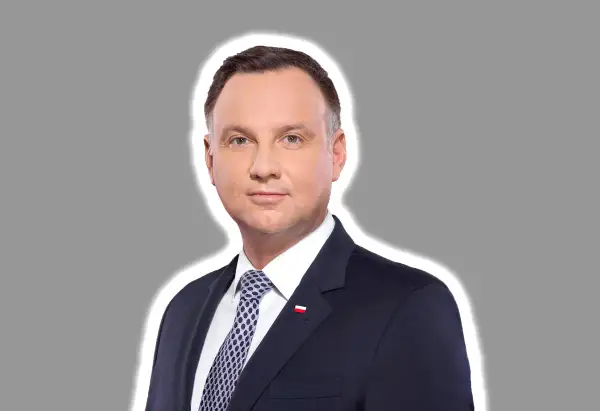 Prezydent Andrzej Duda w garniturze, z biało-czerwoną flagą na klapie. Jego twarz wyraża powagę, jakby rozważał kwestię ułaskawienia.